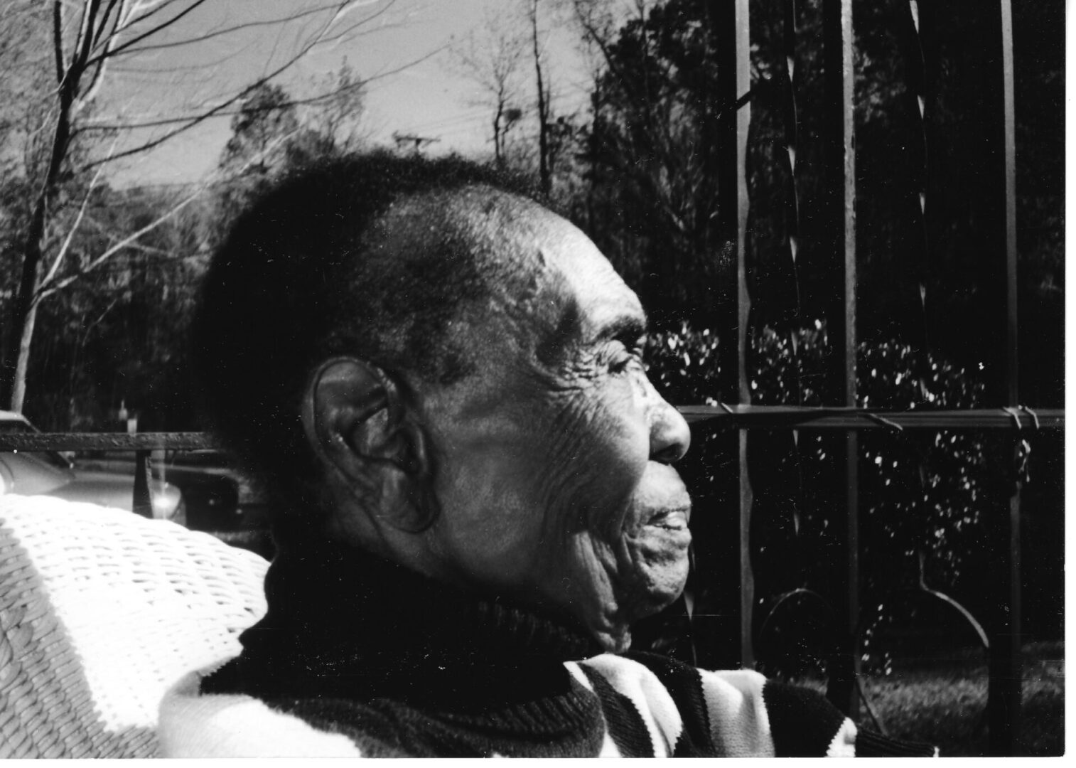 An old man sitting in a chair outside.