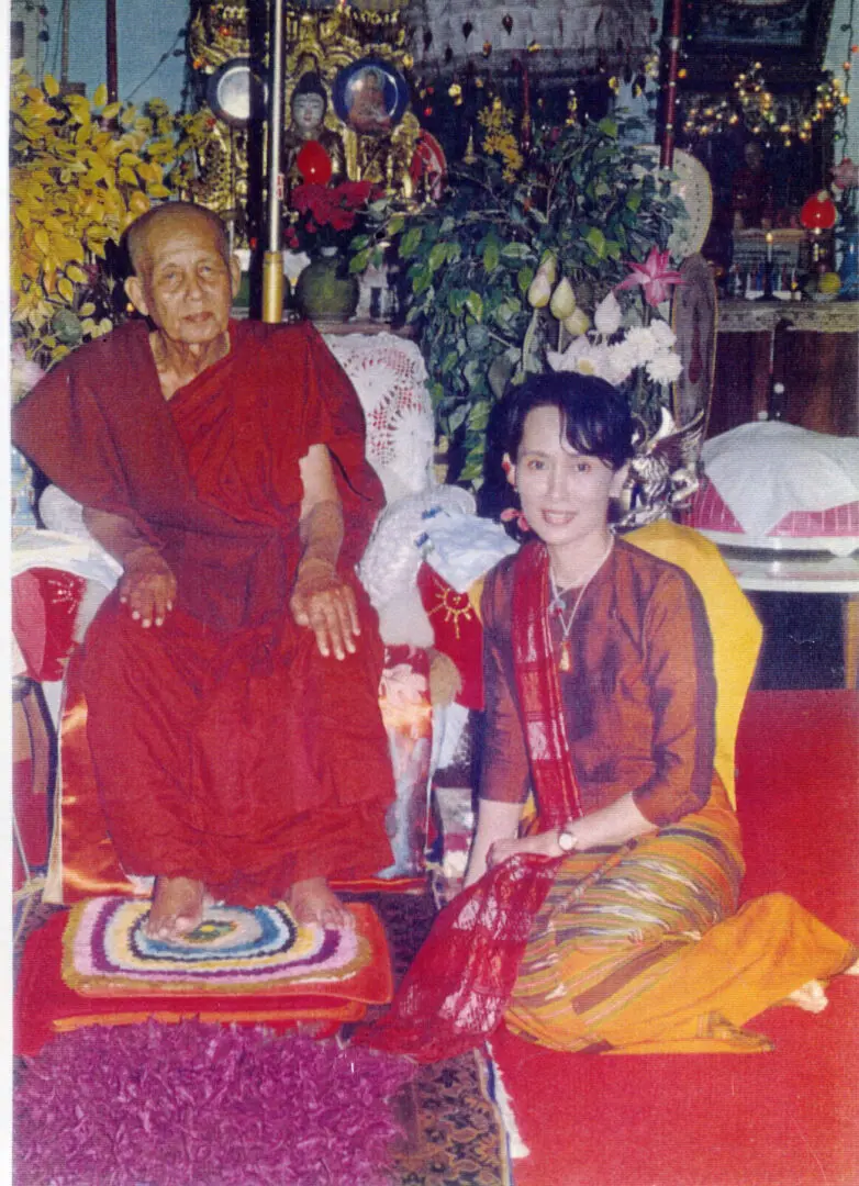 A woman sitting next to an old man in a chair.