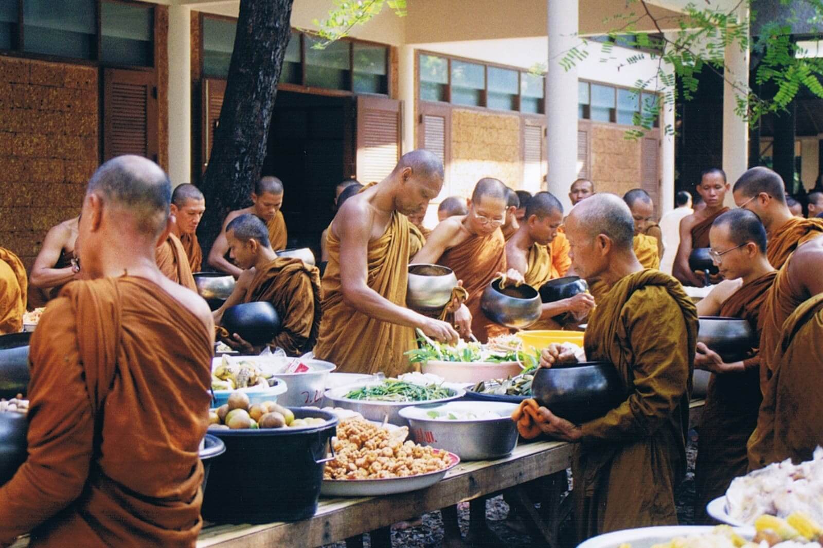 Monks gathering food at a communal table.