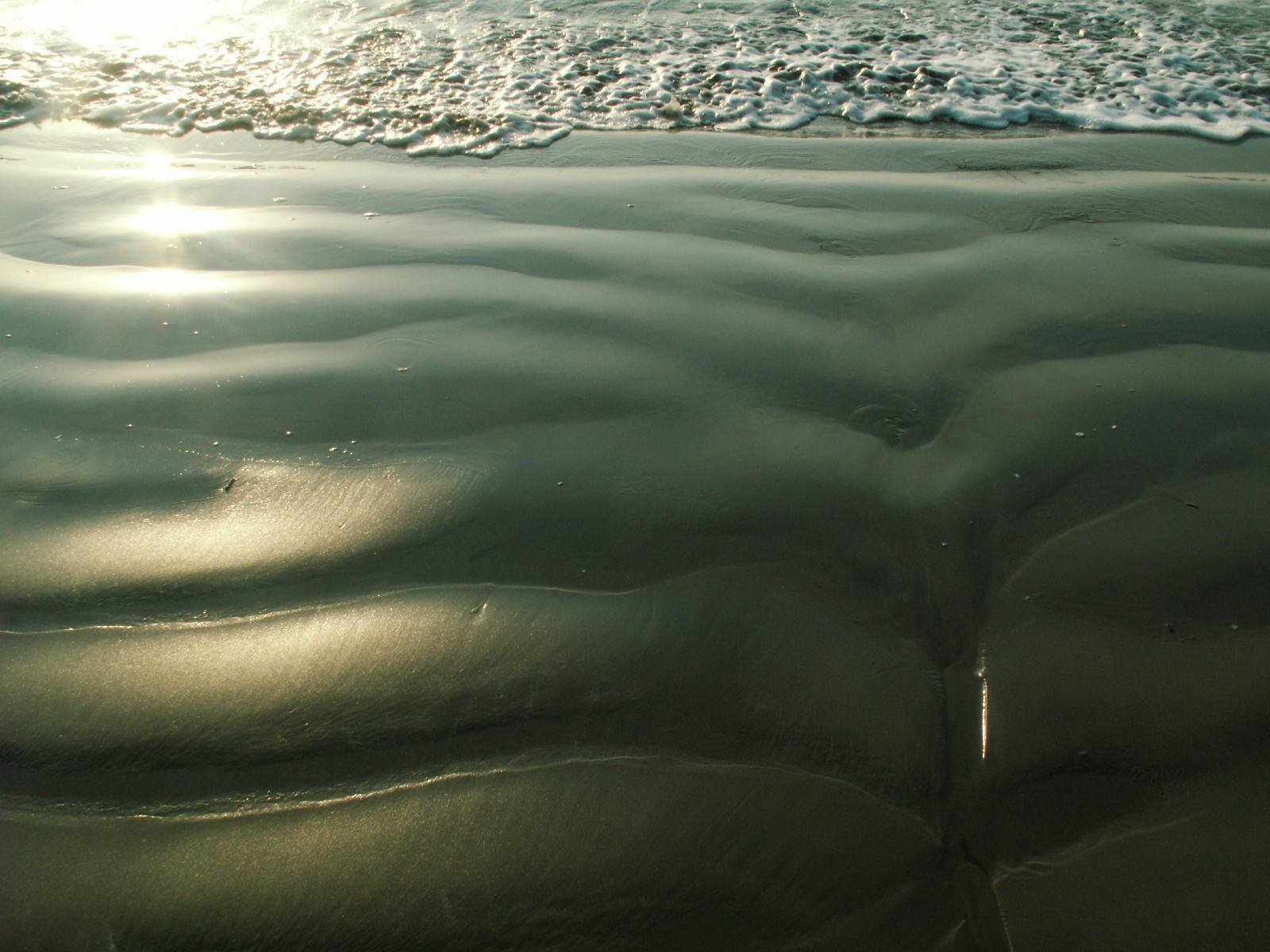 Sunlit ripples on a sandy beach.